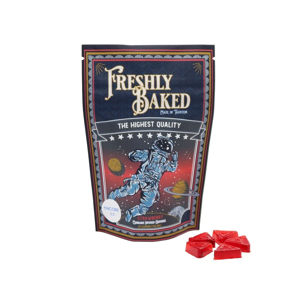 Navy Freshly Baked pouch with an astronaut illustration and The Highest Quality banner, beside red triangular gummies.