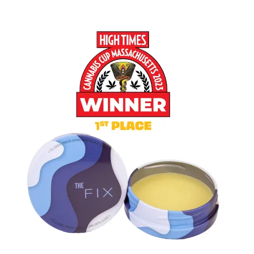 Open round tin of The Fix topical balm with a blue and white wave-pattern lid, showing yellow balm inside.