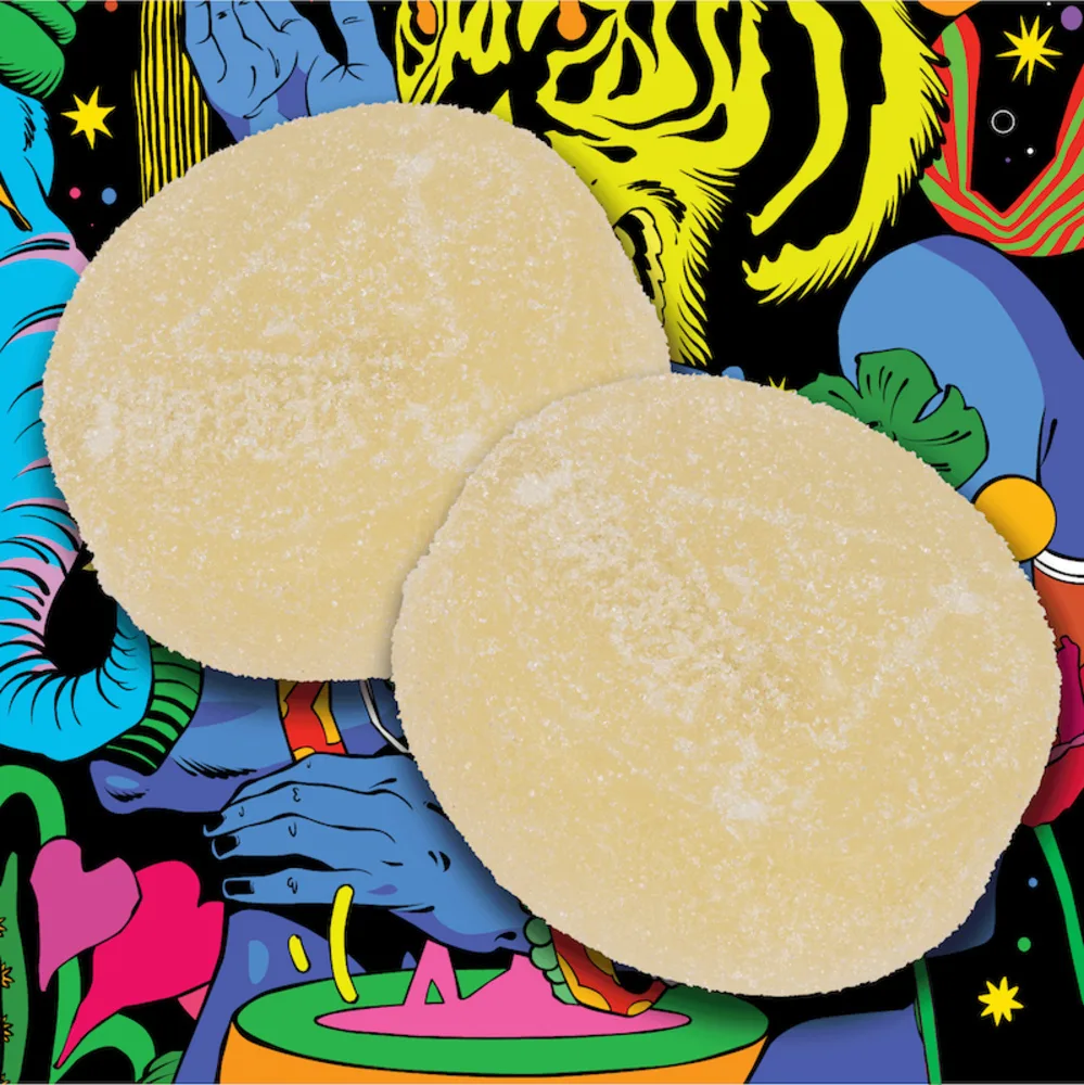 Two pale yellow sugar-coated round gummies on a brightly colored illustrated background.
